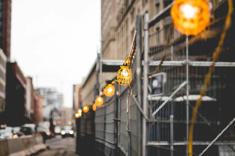 a street filled with lots of traffic next to tall buildings, by Niko Henrichon, pexels contest winner, temporary art, yellow lanterns, rusty chain fencing, industrial lighting, bokeh. chrome accents