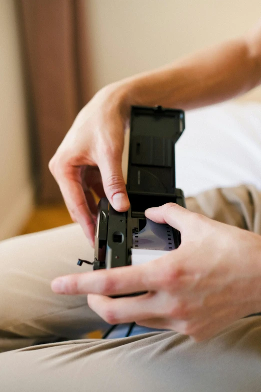 a person sitting on a bed holding a cell phone, wearing an ammo belt, auto graflex, playing games, close up photograph