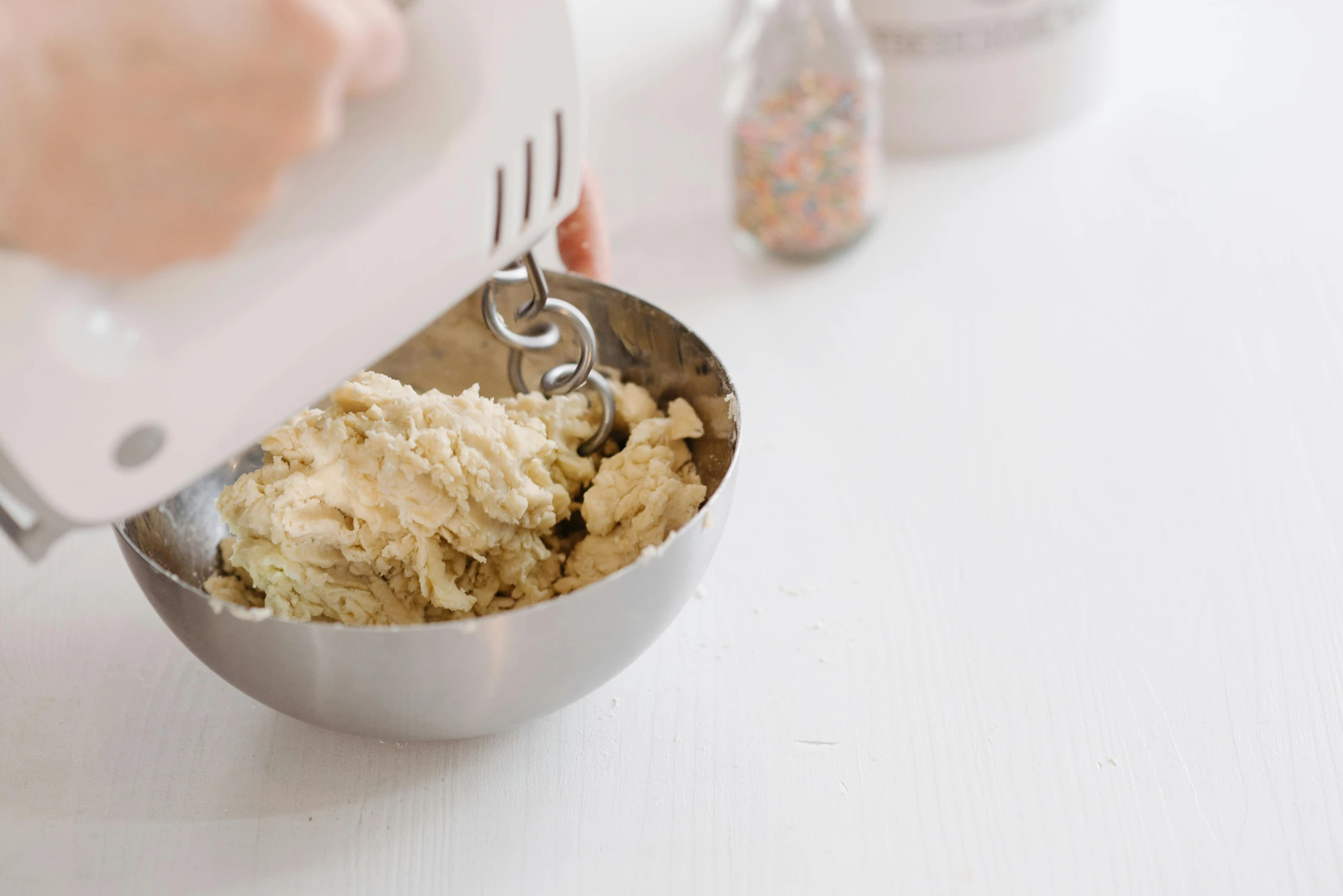 a person mixing food in a bowl on a table, bedhead, silver，ivory, baking cookies, press shot