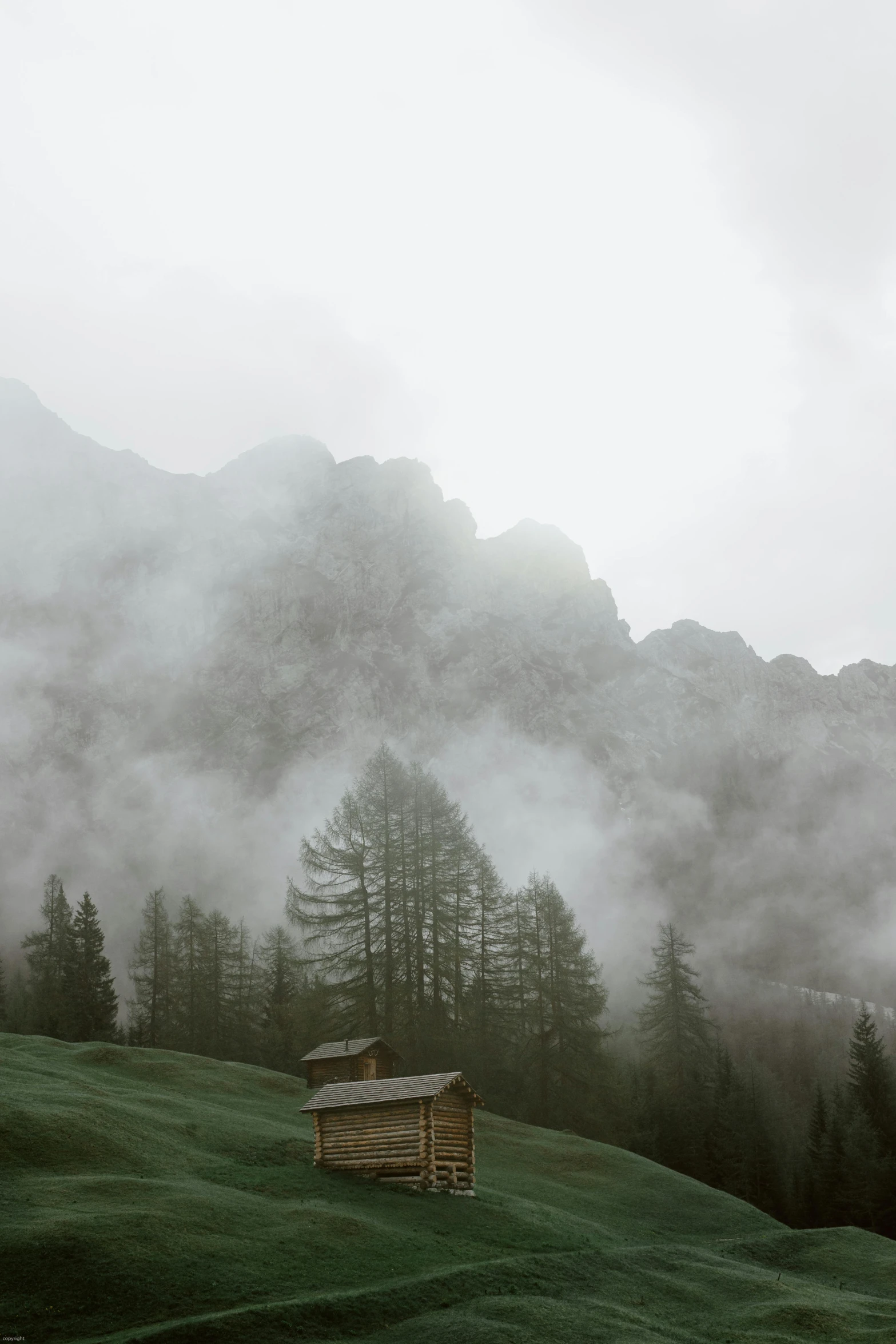 a small cabin sitting on top of a lush green hillside, by Johannes Voss, pexels contest winner, romanticism, overcast gray skies, dolomites, made of mist, dusting of snow