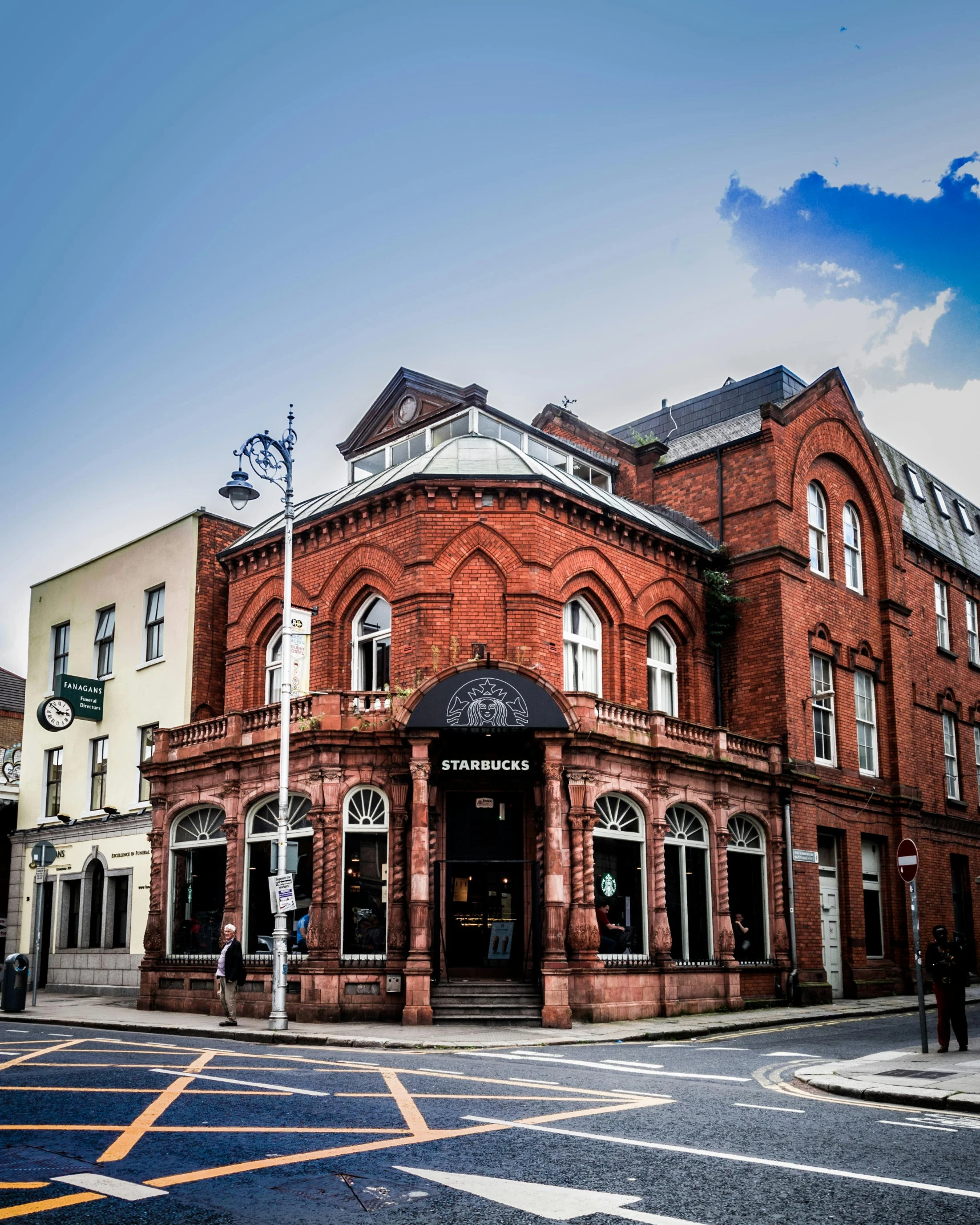 a red brick building sitting on the corner of a street, ancient irish, lgbtq, victoriana, smirking