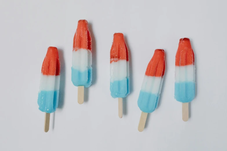 four pops sitting next to each other on a white surface, unsplash, fourth of july, icicle, recipe, blue orange