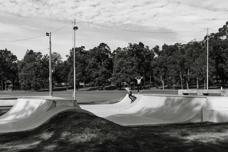 a man riding a skateboard up the side of a ramp, a black and white photo, sydney park, bowl, woamn is curved, in liquid