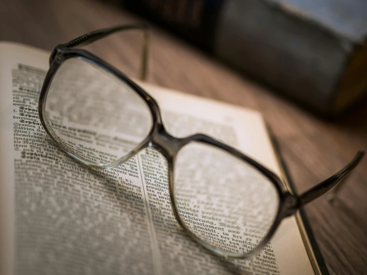 a pair of glasses sitting on top of an open book, square glasses, rich evans, up-close, medium closeup