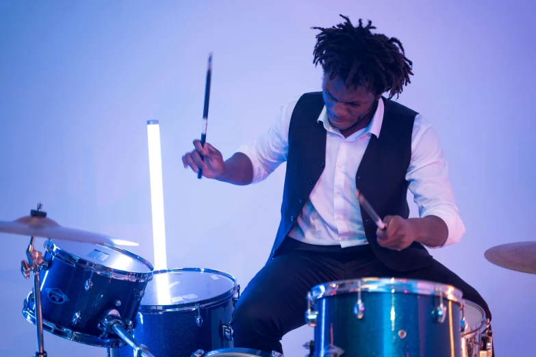 a man sitting on top of a drum kit, by Stokely Webster, unsplash, bright glowing instruments, set against a white background, blue period, beautiful surroundings