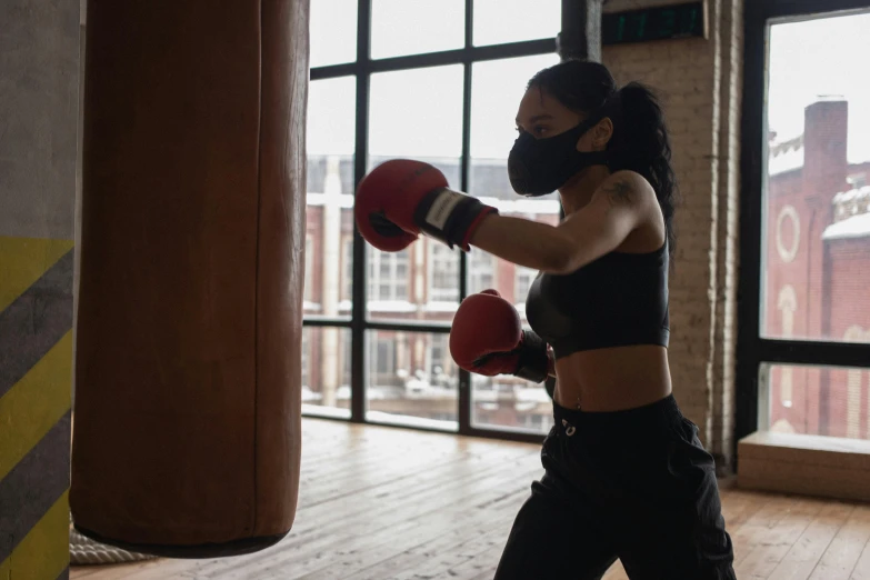 a woman in a black top and red boxing gloves, pexels contest winner, masked person in corner, working out, 🦩🪐🐞👩🏻🦳, hazy