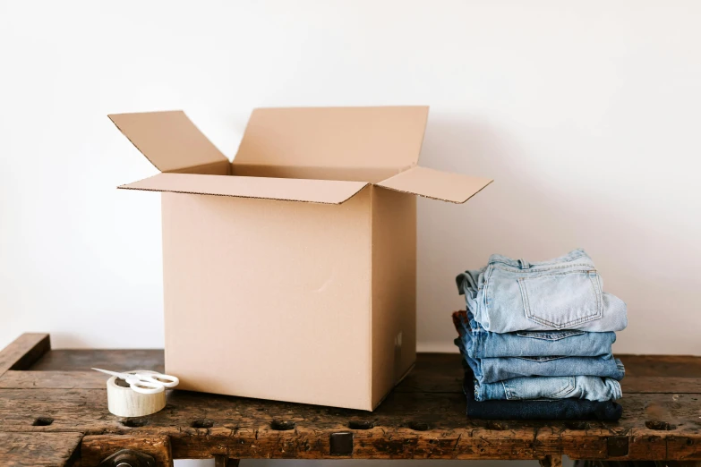 a cardboard box sitting on top of a wooden table, jeans and t shirt, blue clothes, thumbnail, small room