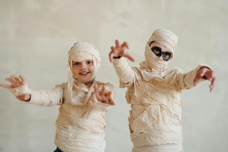 two children dressed as mummys pose for a picture, pexels contest winner, mummified in bandages, profile image, cardboard, triumphant pose