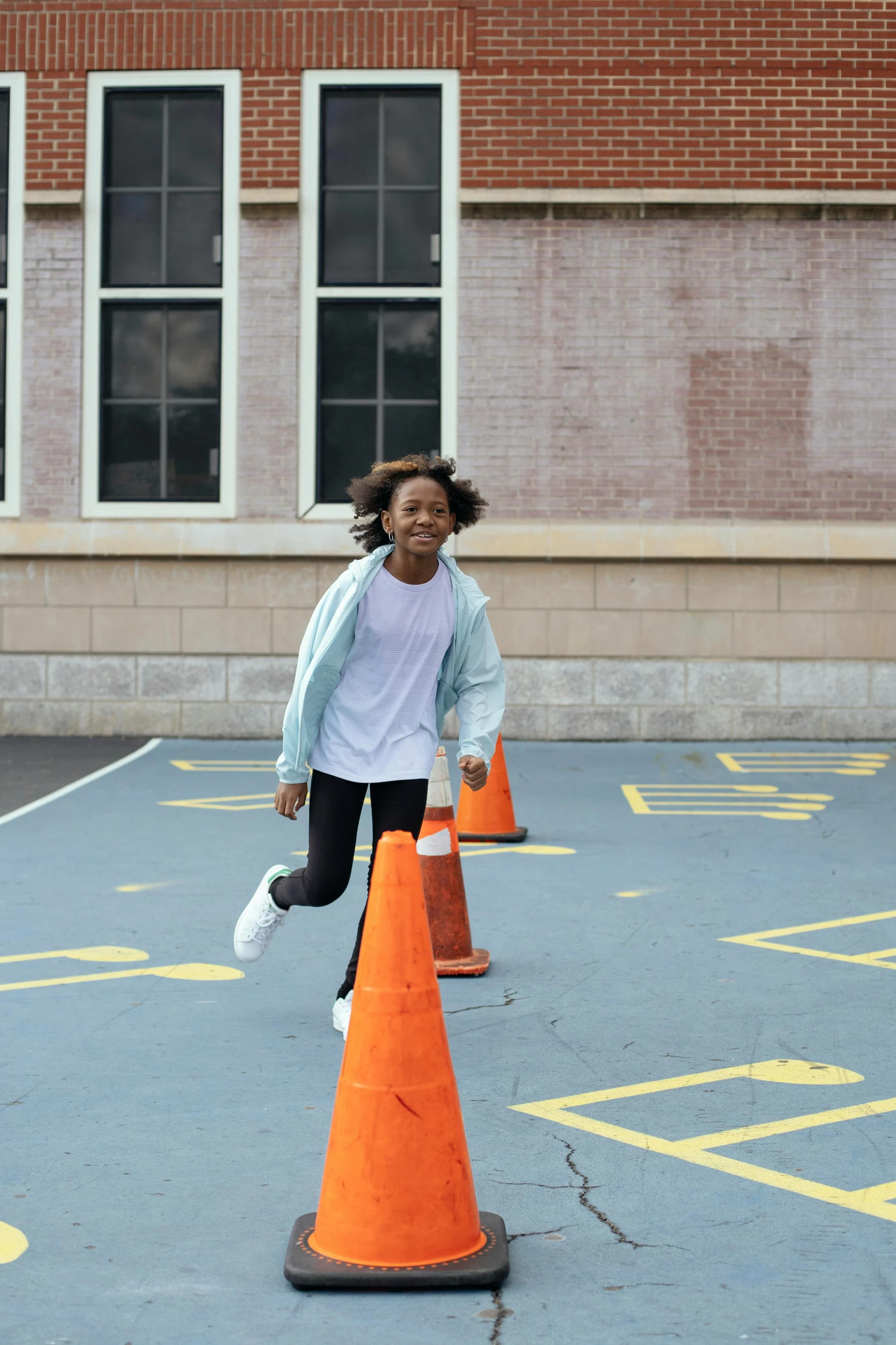 a young girl running around orange cones in a parking lot, by Carey Morris, happening, black teenage boy, school courtyard, promo image, confident pose