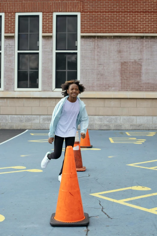 a young girl running around orange cones in a parking lot, by Carey Morris, happening, black teenage boy, school courtyard, promo image, confident pose