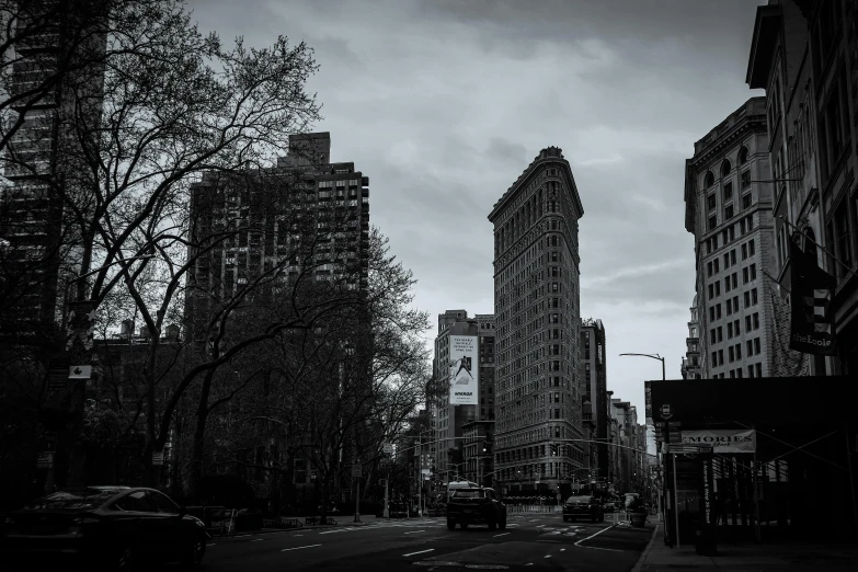 a black and white photo of a city street, inspired by Vivian Maier, unsplash contest winner, art nouveau, madison square garden, today\'s featured photograph 4k, victorian buildings, twilight in the city