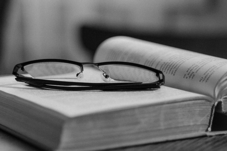 a pair of glasses sitting on top of a book, a black and white photo, by Karl Buesgen, facebook photo, morning detail, library books, uploaded