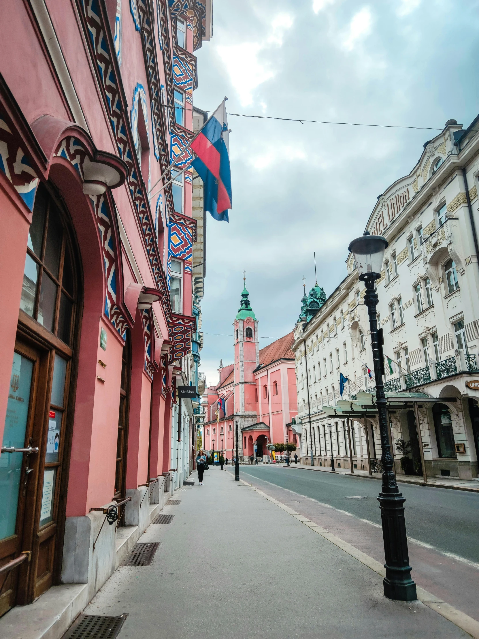 a narrow street with a clock tower in the background, art nouveau, pink and red colors, photo of džesika devic, square, pink and blue