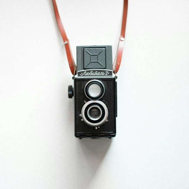 a close up of a camera on a white surface, by Lubin Baugin, unsplash, rolleiflex, black and brown colors, a black choker, vintage color photo