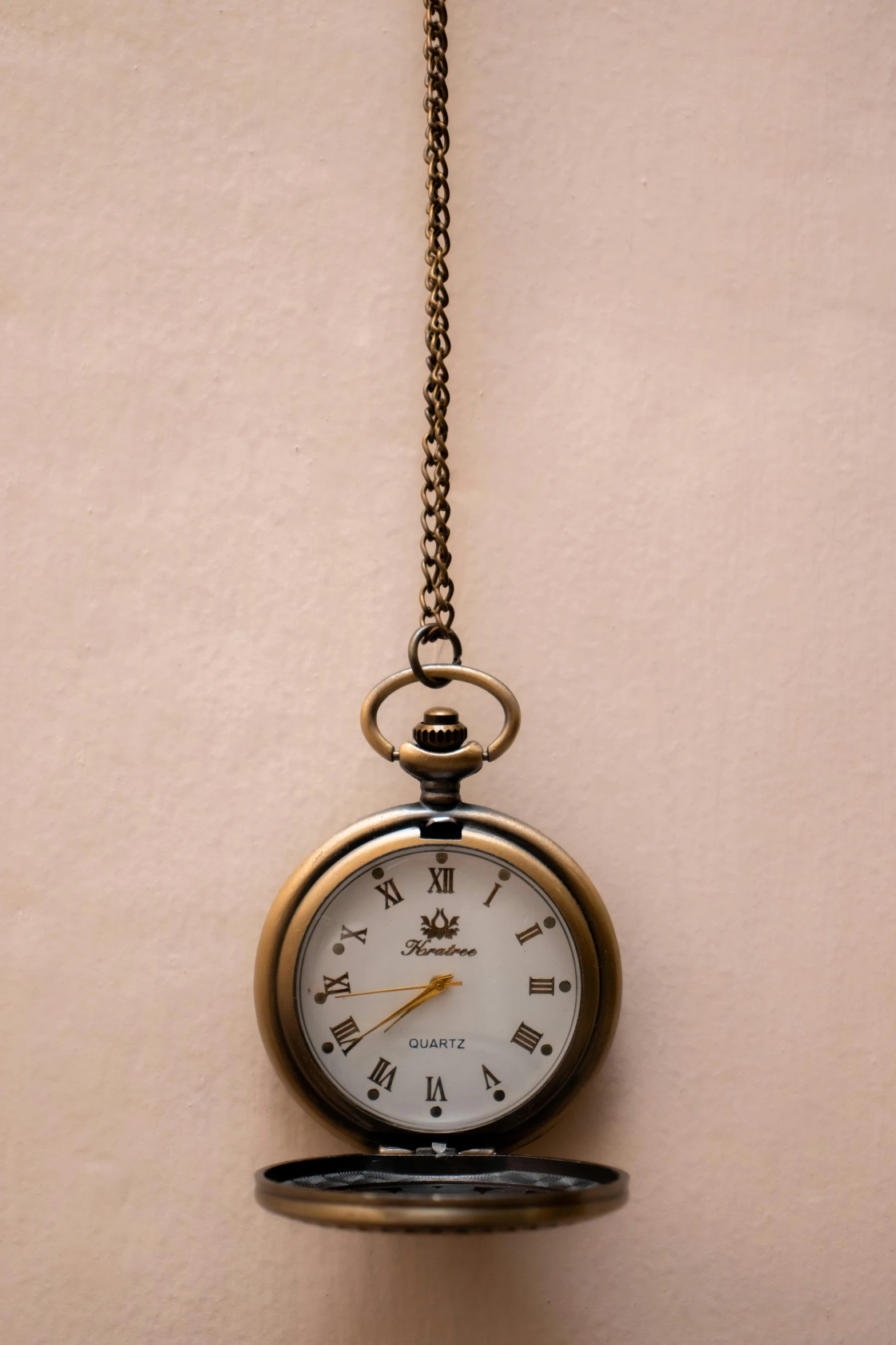 a clock hanging from a chain on a wall, by Andries Stock, unsplash, minimalism, close up shot of an amulet, brown, thumbnail, shot on sony a 7