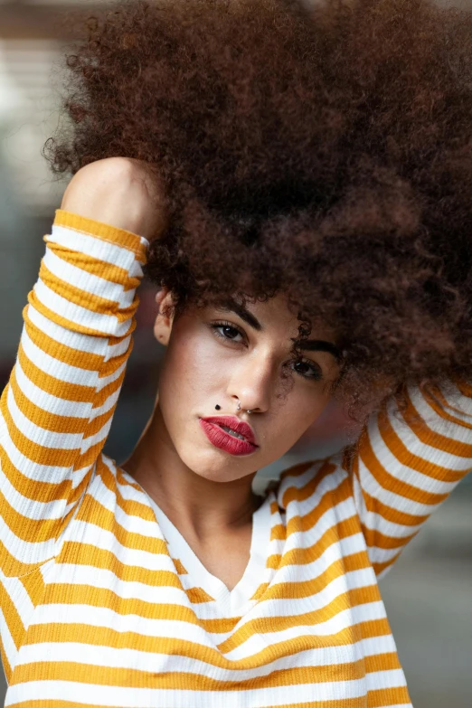 a woman with an afro is posing for a picture, inspired by Elsa Bleda, trending on pexels, renaissance, striped, mustard, large eyebrows, brown haired