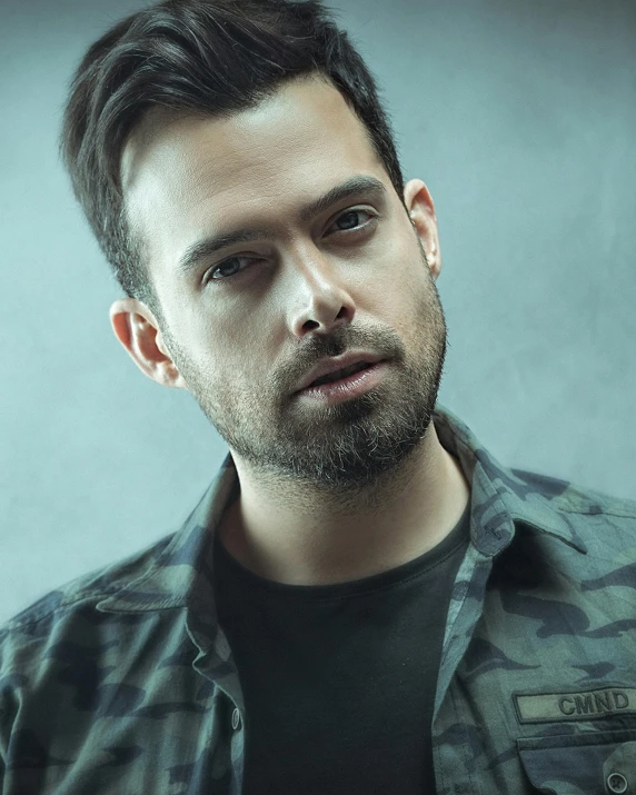 a man with a beard wearing a camo shirt, by Adam Dario Keel, promo photo, despacito, lgbtq, looking out