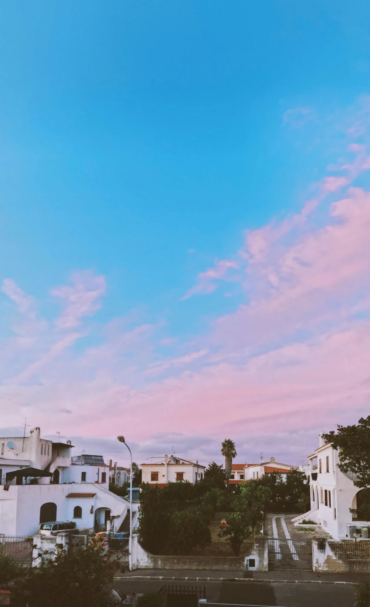 a couple of buildings that are next to each other, by Olivia Peguero, unsplash contest winner, aestheticism, panorama view of the sky, pink white turquoise, late afternoon, white houses