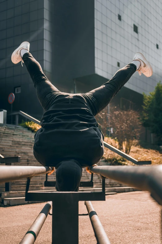 a person doing a handstand in front of a building, sitting on a bench, looking down on the camera, benches, portrait featured on unsplash