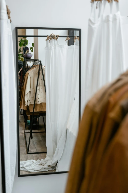 a bed room with a bed and a mirror, by Jan Tengnagel, trending on unsplash, long white cape, exiting store, brown clothes, on display