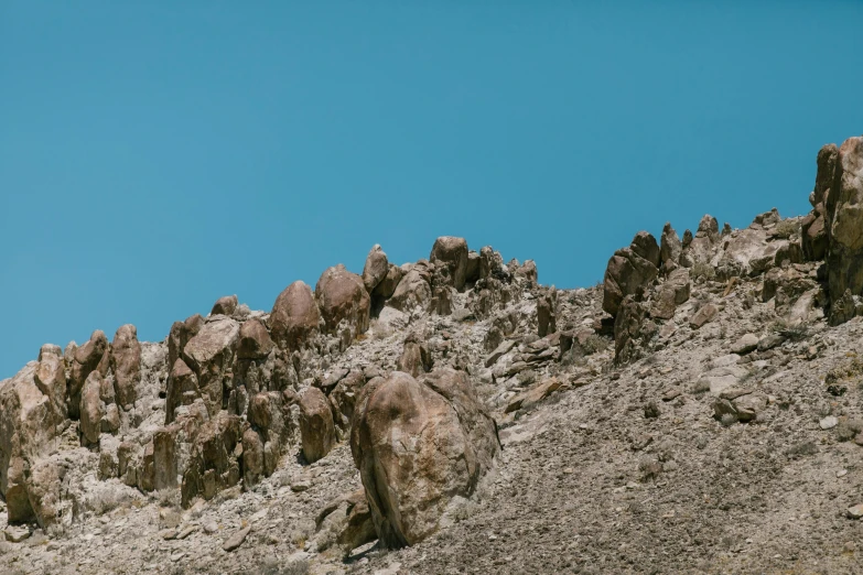 a herd of sheep standing on top of a rocky hillside, an album cover, unsplash, figuration libre, clear blue skies, ((rocks)), minimalist photo, rock climbers climbing a rock