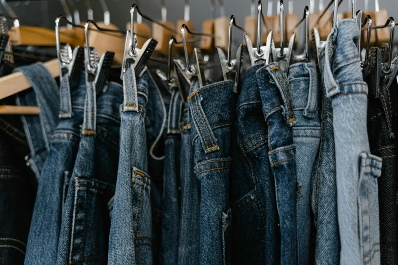a rack of jeans hanging on a clothes rack, trending on pexels, 🦩🪐🐞👩🏻🦳, hyper-realistic, clones, zoomed in