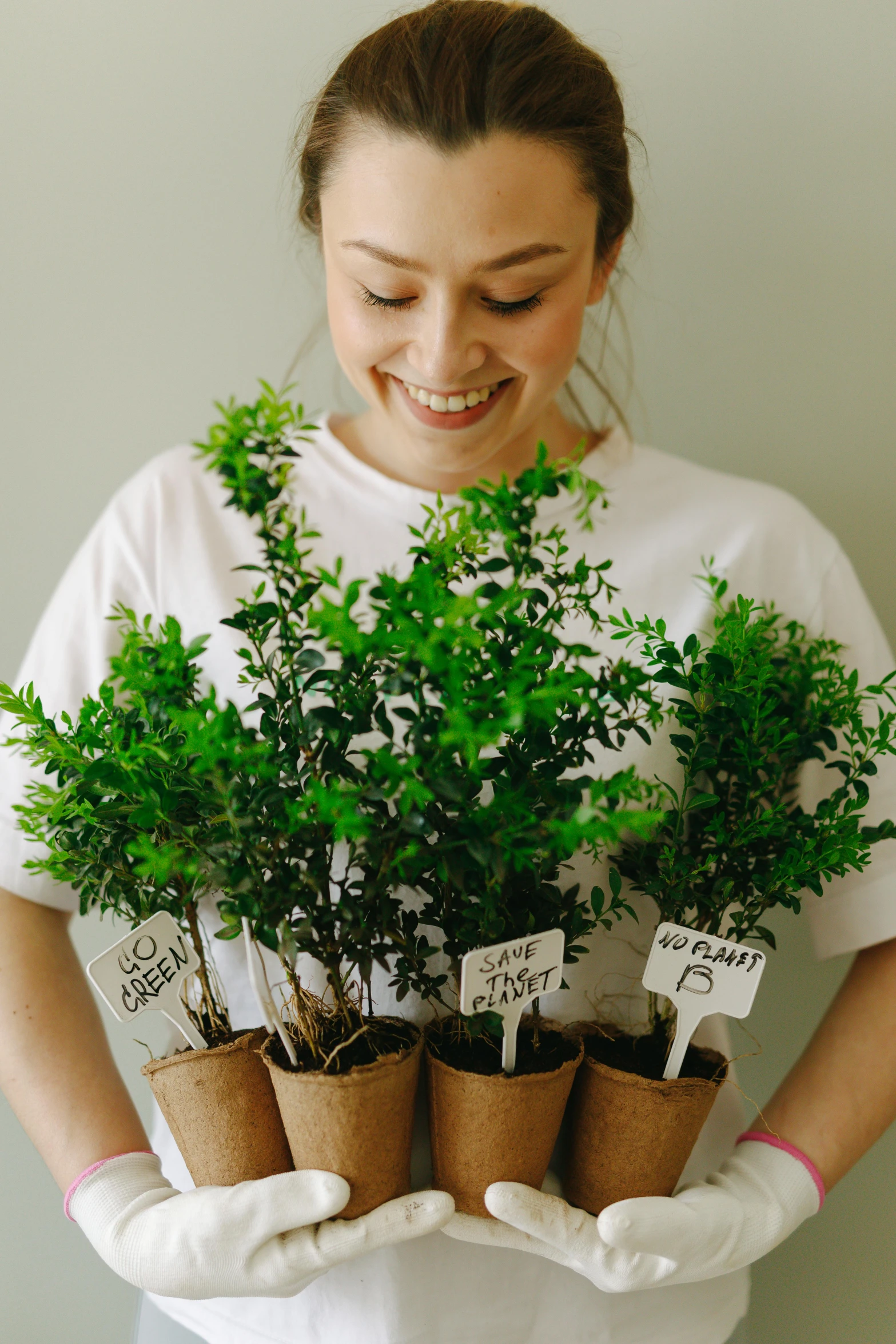 a woman holding a bunch of potted plants, cherished trees, lush and green, honeysuckle, sustainable materials