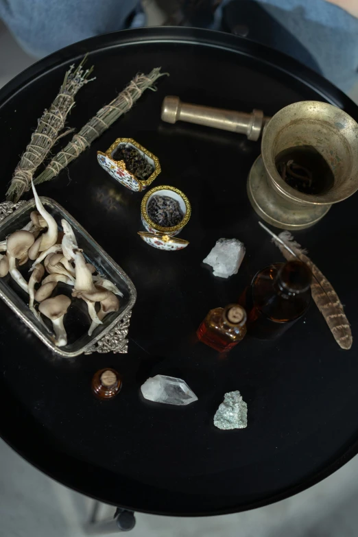 a black table topped with assorted items, inspired by Li Di, unsplash, assemblage, shrooms, apothecary, close up shot of an amulet, detailed product image