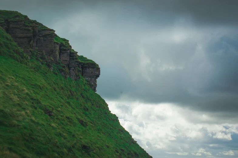 a couple of sheep standing on top of a lush green hillside, an album cover, by Elsa Bleda, pexels contest winner, extremely detailed rocky crag, ancient irish, stormy clouds, photo taken from a boat