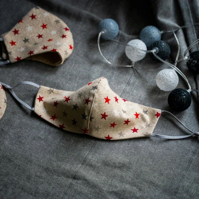 a pair of face masks with red stars on them, by Emma Andijewska, beige, festive atmosphere, ready - made, linen