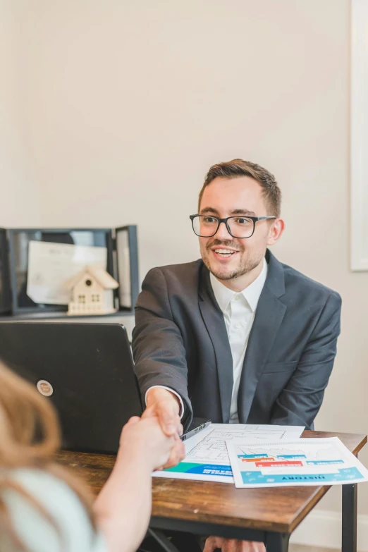 a man in a suit shaking hands with a woman, brandon, profile image, an estate agent listing photo, wearing a suit and glasses