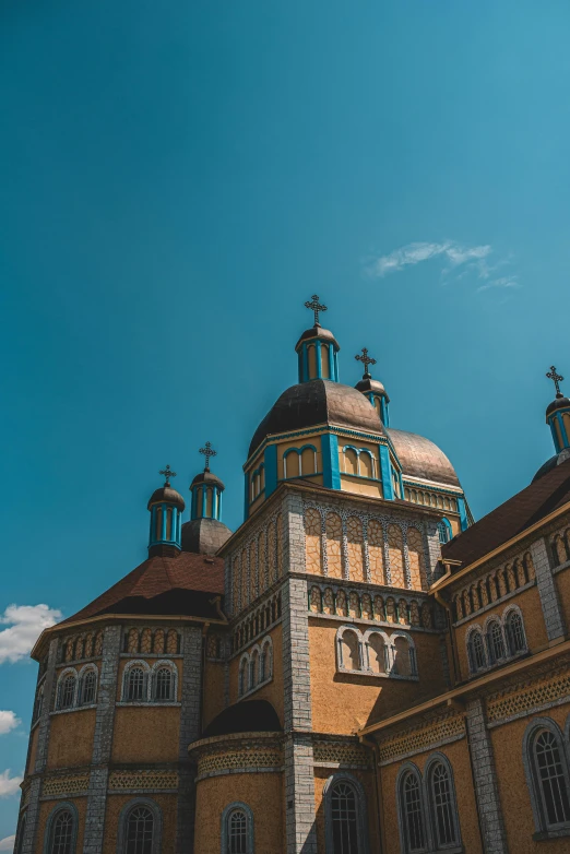 a large building with a blue sky in the background, by Adam Marczyński, unsplash contest winner, baroque, orthodox christianity, domes, transylvania, brown and cyan color scheme