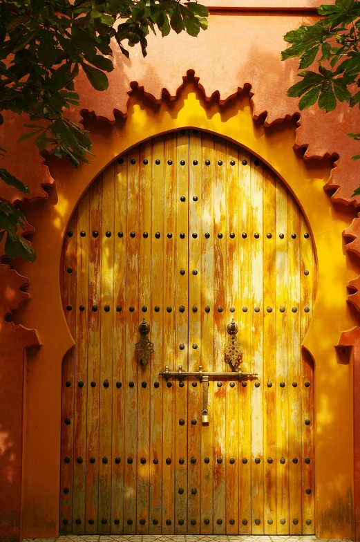 a wooden door that is on the side of a building, inspired by Riad Beyrouti, orange yellow ethereal, lush surroundings, archs