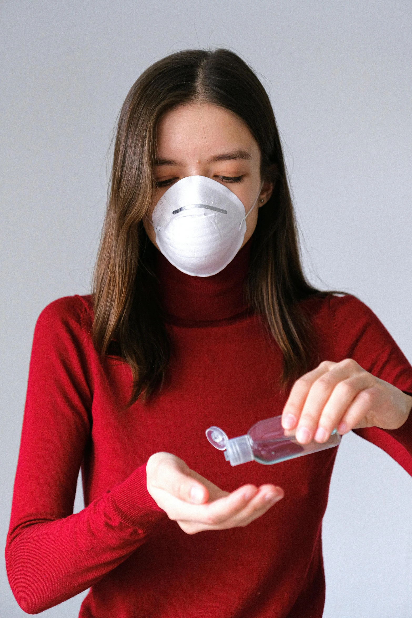 a woman in a red shirt is putting a mask on her face, wearing nanotech honeycomb robe, carrying a bottle of perfume, turbulence, white