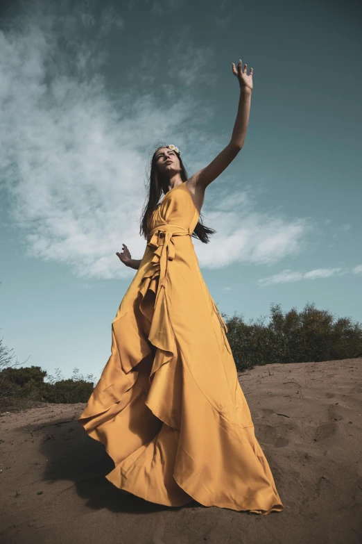 a woman in a yellow dress standing in the sand, pexels contest winner, renaissance, victorious on a hill, at a fashion shoot, promotional image, long dress