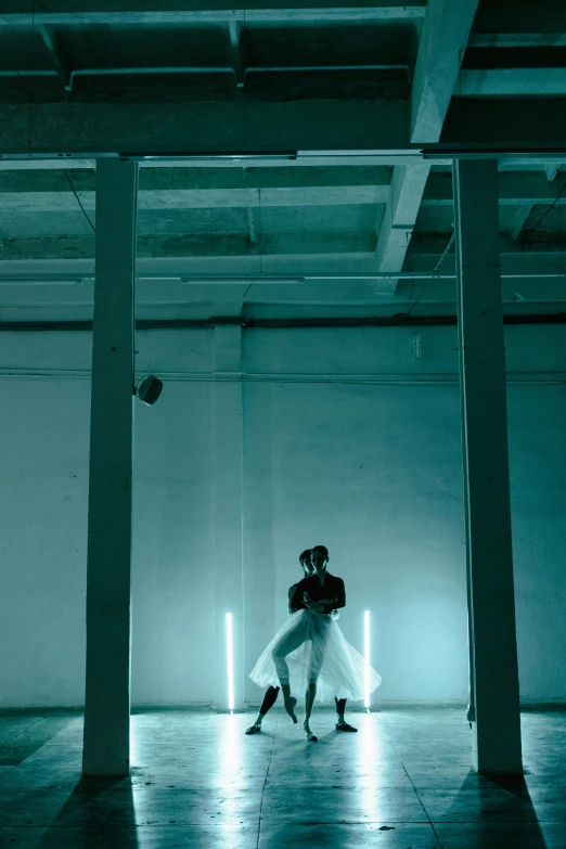 a couple of people that are standing in a room, an album cover, inspired by Elsa Bleda, unsplash, light and space, dancer, in a warehouse, dan flavin, teal lighting