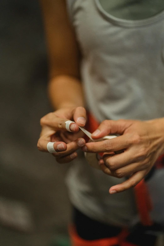 a close up of a person holding a cell phone, white bandage tape on fists, in a workshop, shot with sony alpha, neat nails
