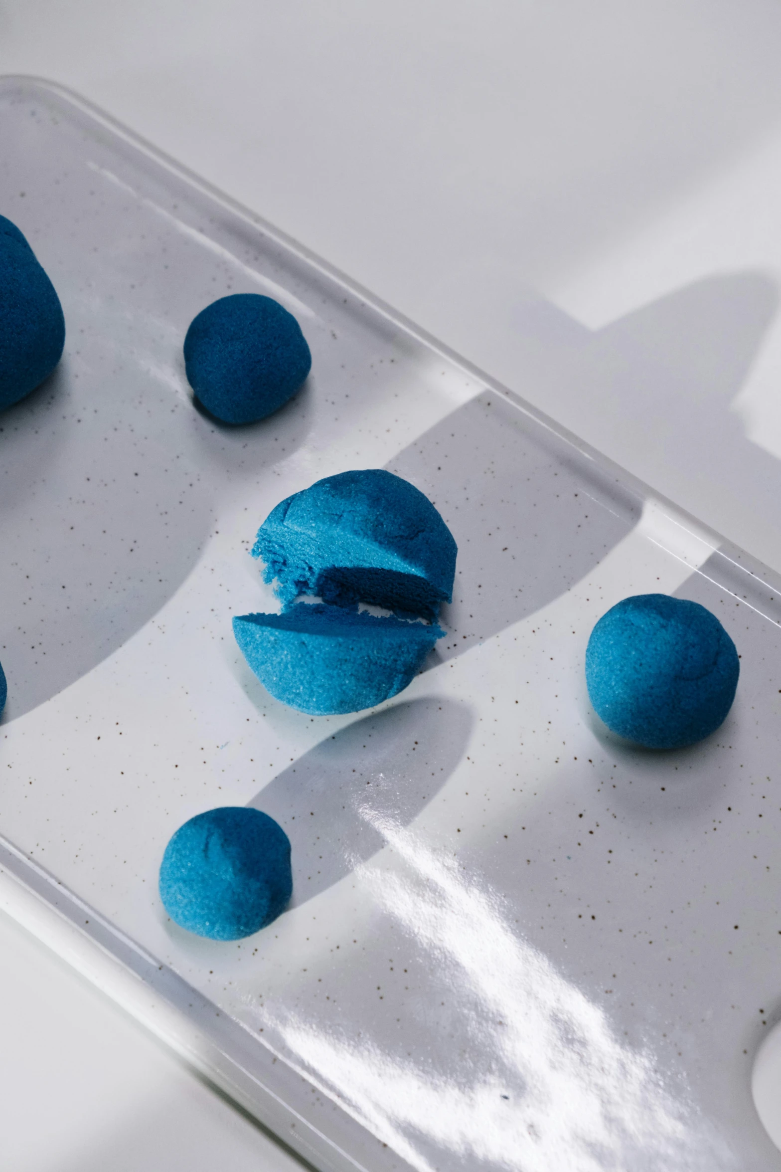 a close up of a tray of doughnuts on a table, an abstract sculpture, inspired by Yves Klein, unsplash, process art, blue sand, floating spheres and shapes, matte finish, angled