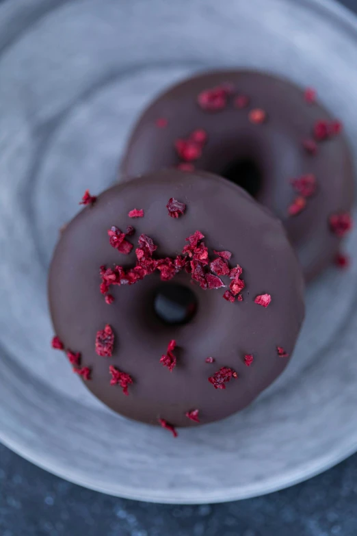 two chocolate donuts with sprinkles on a plate, a portrait, by Jessie Algie, hurufiyya, dark red, buds, 1x, dark grey