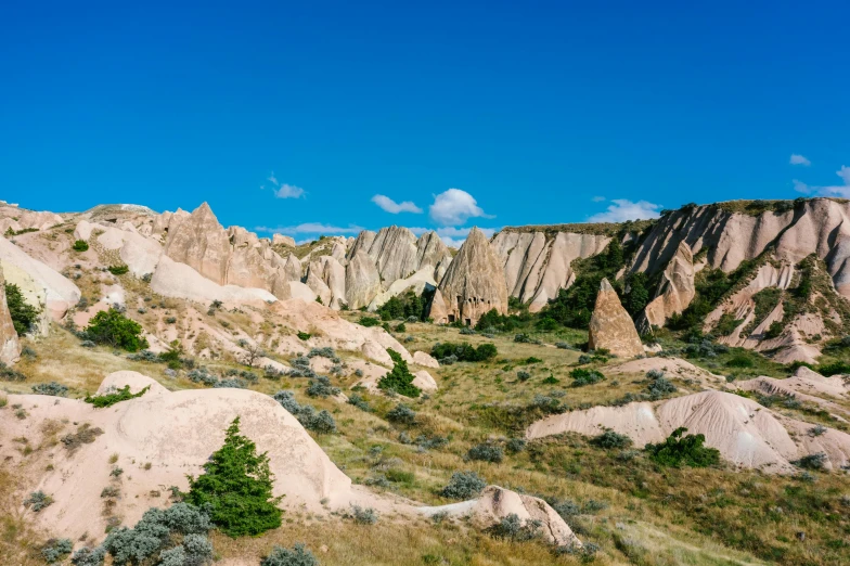 a rocky landscape with a blue sky in the background, by Muggur, trending on unsplash, art nouveau, cypresses and hills, white, sandstone, conde nast traveler photo