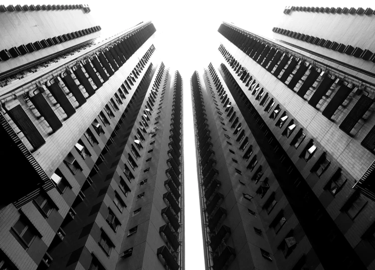 a black and white photo of a tall building, inspired by Cheng Jiasui, pexels, brutalism, three towers, hong kong buildings, low angle fisheye view, mass housing