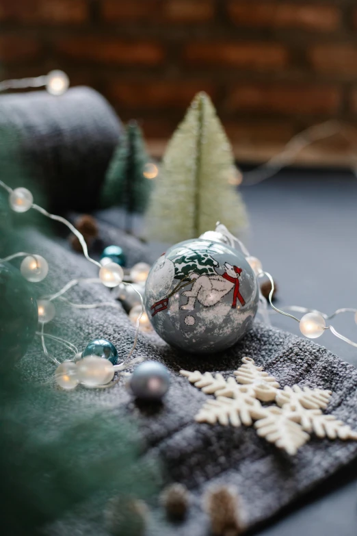 a close up of a christmas ornament on a table, moonlight grey, cosy enchanted scene, peppermint motif, spot lit