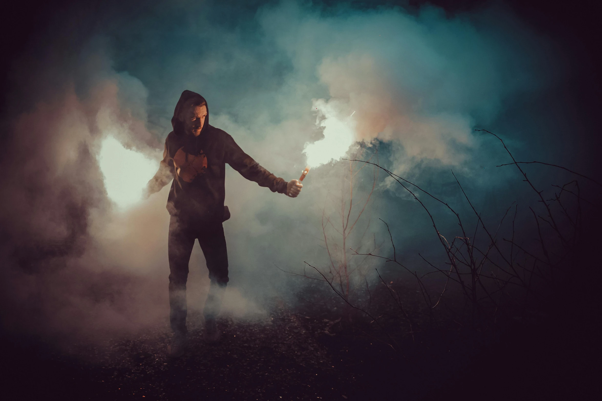 a man standing on top of a grass covered field, an album cover, by Adam Marczyński, pexels contest winner, muzzle flash, small people with torches, dark and moody smoke, halloween