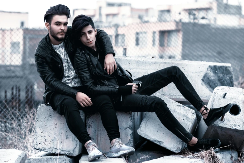 a man and a woman sitting next to each other, trending on pexels, antipodeans, androgynous male, wearing leather, hasan piker, two young men