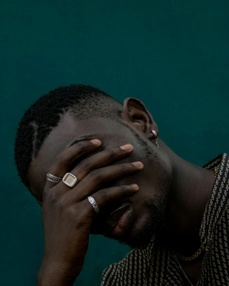 a man covers his face with his hands, an album cover, by Elsa Bleda, trending on unsplash, afrofuturism, crying fashion model, queer, ☁🌪🌙👩🏾, dark green tones