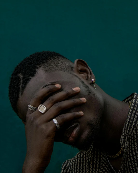 a man covers his face with his hands, an album cover, by Elsa Bleda, trending on unsplash, afrofuturism, crying fashion model, queer, ☁🌪🌙👩🏾, dark green tones