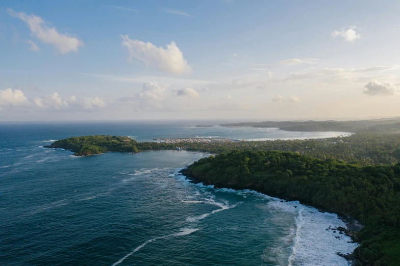 a large body of water next to a lush green hillside, an album cover, pexels contest winner, happening, tropical coastal city, aerial footage, caribbean, beautiful late afternoon