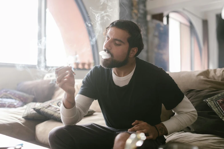 a man sitting on a couch smoking a cigarette, pexels contest winner, renaissance, smoking a bowl of hash together, middle eastern, smoking with squat down pose, trailing white vapor