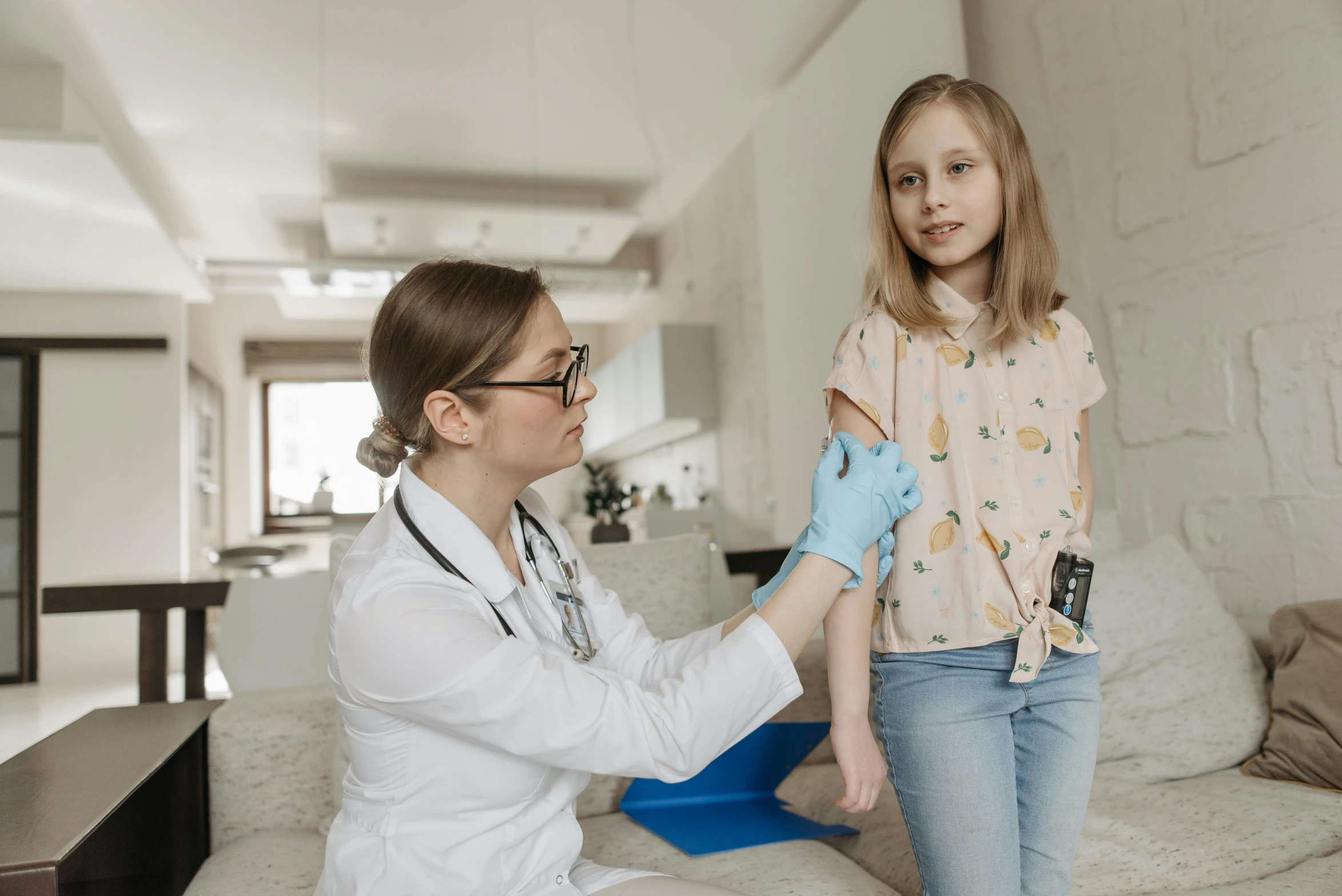 a woman with a stethoscope examining a little girl's arm, by Emma Andijewska, pexels contest winner, holding a syringe, gif, low quality photo, brown