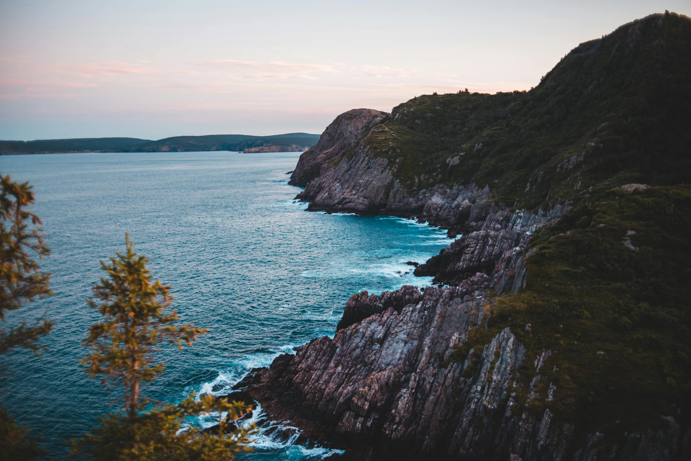 a view of the ocean from the top of a hill, by Kyle Lambert, pexels contest winner, cliff side at dusk, quebec, coastal cliffs, mauve and cyan